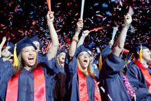 students cheering in graduation regalia 